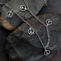 Silver-colored stainless steel anklet with a cable style chain draped over rocks, featuring five peace sign charms.