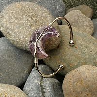 Wire-Wrapped Amethyst Moon Bracelet resting on river rocks, offering an alternative view of the crescent and tree motif.