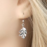 Closeup of a Silver Oak Leaf Earring in a model’s ear, showcasing the lifelike leaf and a small silver bead on the hook.