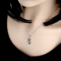 The Silver Thistle Luckenbooth Pendant is being worn on a chain around a woman's neck, showing its light, airy appearance.