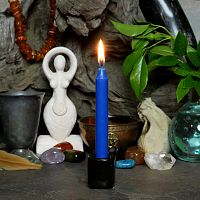 A lit royal blue chime candle, in a personal altar display, showing how it might be used in a ritual or ceremonial setting.