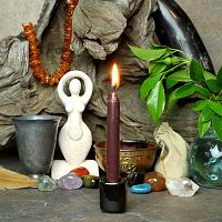 A lit brown chime candle, in a personal altar display, showing how it might be used in a ritual or ceremonial setting.