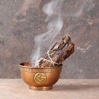 Smoldering Yerba Santa Bundle with a thin stream of smoke, propped in a small copper bowl that sits on fireproof tile surface