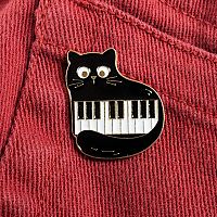 The Piano Cat Enamel Pin worn on brick-red denim jeans, showcasing its casual charm. Perfect for music- and cat-lovers.