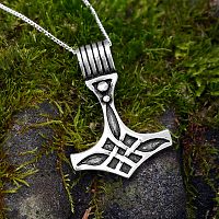 Sterling Silver Thor's Hammer Pendant propped against a mossy carven stone, suggesting this design's ties to the past.
