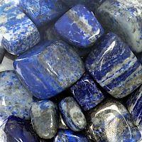 Tumbled Lapis Lazuli gemstones, in a deep rich blue color with grey-white matrix, mottled patterns, and subtle pyrite sheen.