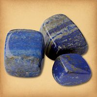Three tumbled Lapis Lazuli stones, in a deep blue color with a grey matrix, demonstrating the typical variety in a set.