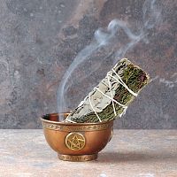 Smoldering Sage and Cedar Bundle with a trickle of smoke, propped in a small copper bowl that sits on fireproof tile surface.
