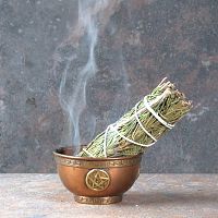 Smoldering Rosemary Herb Bundle with a trickle of smoke, propped in a small copper bowl that sits on fireproof tile surface.