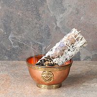Smoldering Sage and Lavender Bundle with a trickle of smoke, propped in a small copper bowl that sits on a fireproof surface.
