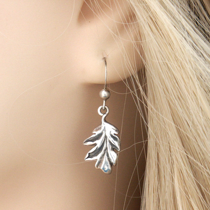 Closeup of a Silver Oak Leaf Earring in a model’s ear, showcasing the lifelike leaf and a small silver bead on the hook.