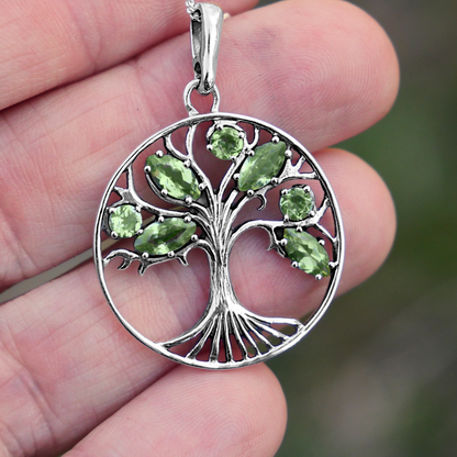 Sterling Silver Peridot Tree Pendant held between fingertips, highlighting the fine details in the tree’s roots and branches.