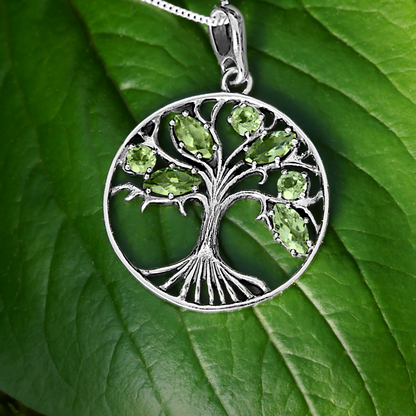 Sterling Silver Peridot Tree Pendant displayed on a vibrant green leaf in natural lighting. So lovely and meaningful!