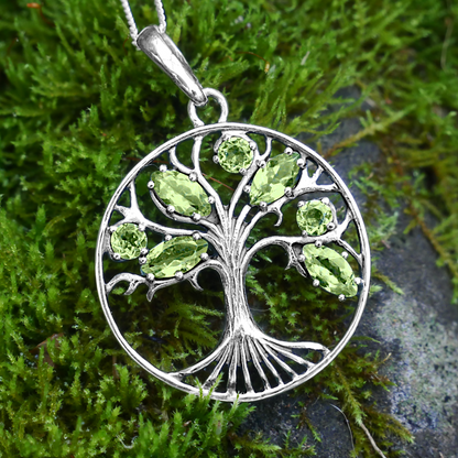 Sterling Silver Peridot Tree Pendant, displayed on mossy bank, highlighting its spiritual connection to growth and vitality.